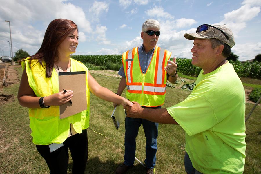 Morgan Drewek shakes hands with the foreman of the construction site being inspected as mentor David Kapitan looks on.